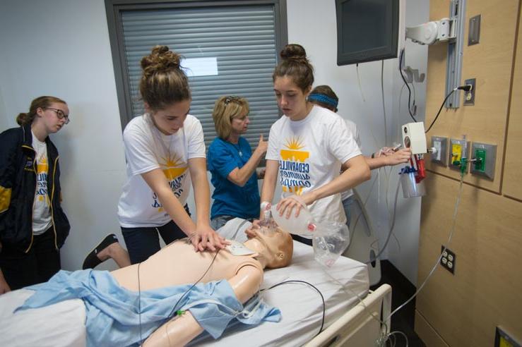 Two female students practice CPR on a mannequin